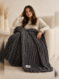 Akumi Anchor Blanket in Warm Slate draped over lounge chair with Akumi woven label