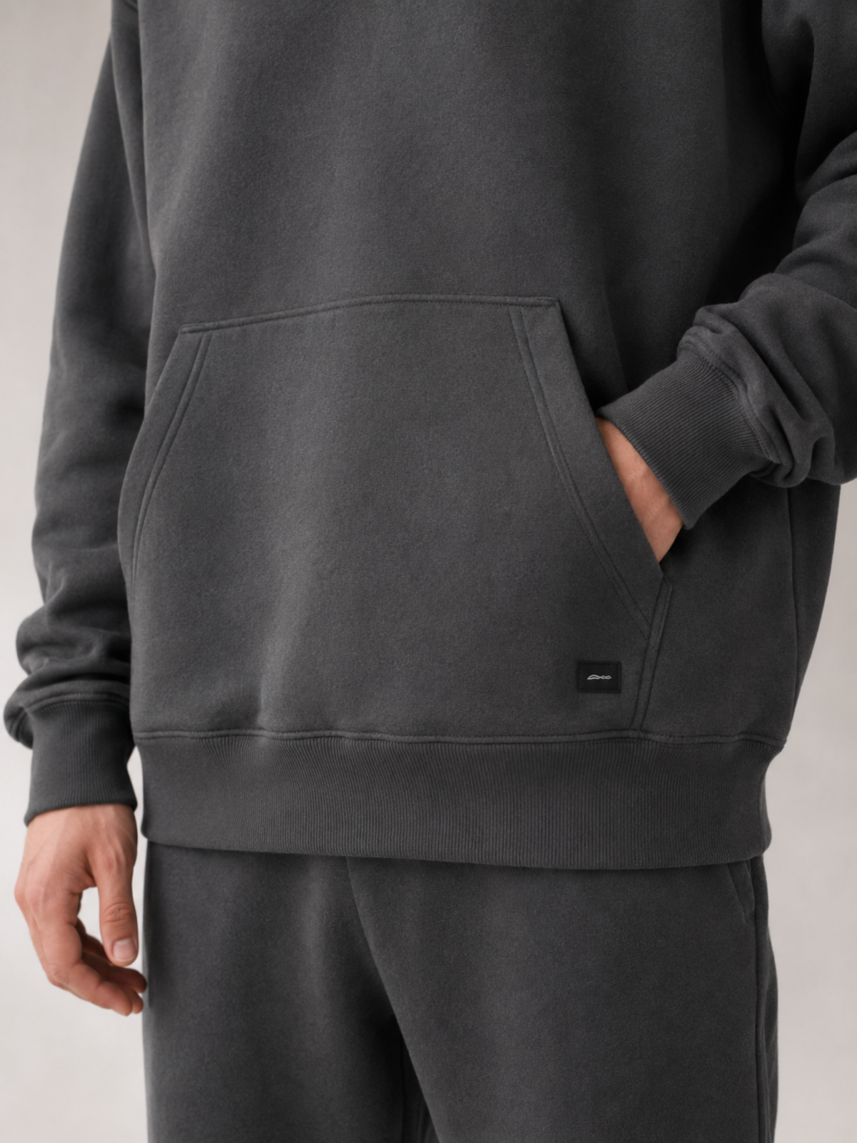 Pocket, fleece and woven patch detail of Akumi Collegiate Motion Hoodie