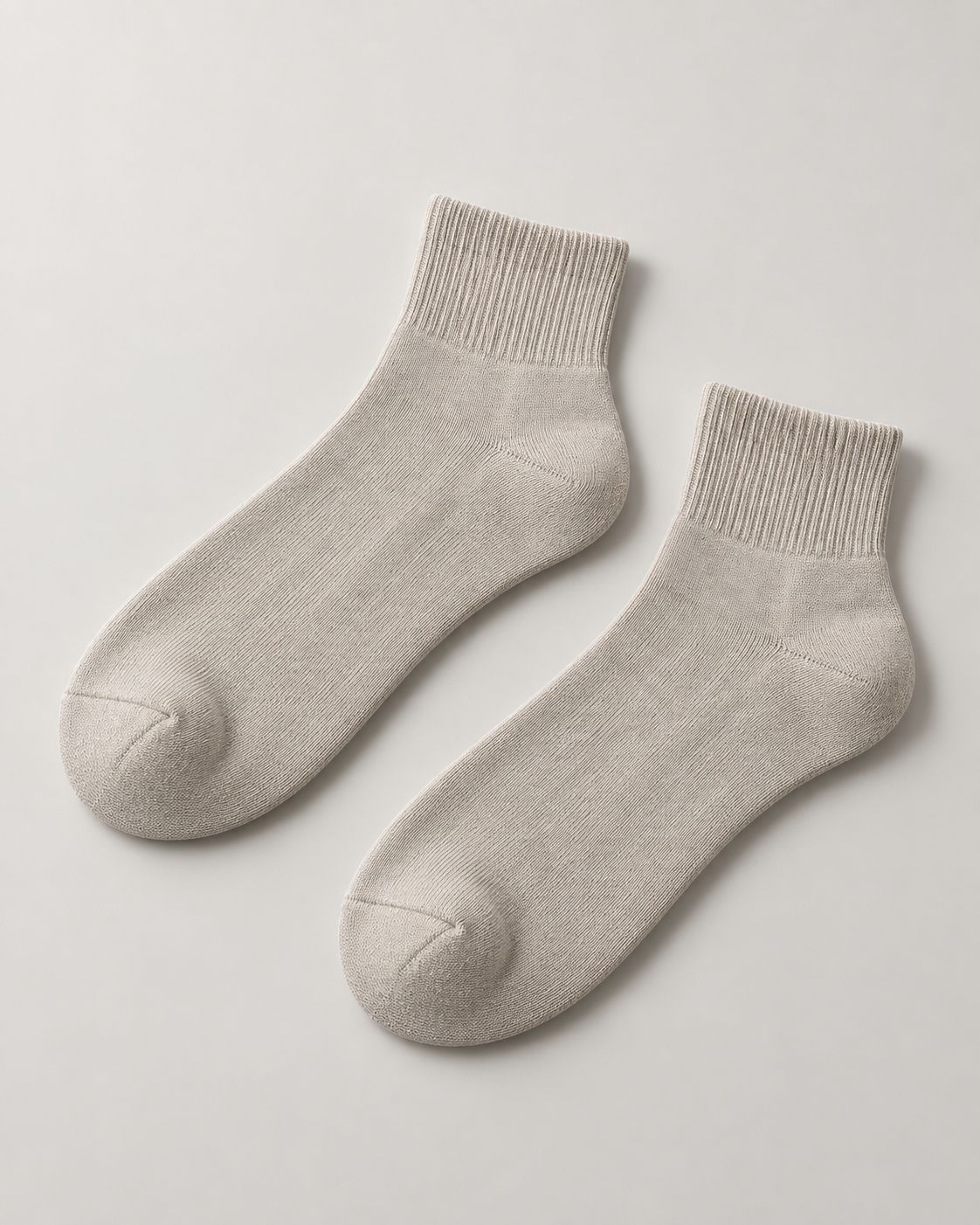Concept mockup of a pair of stone Akumi Everyday Quarter Socks with short ribbed cuffs.