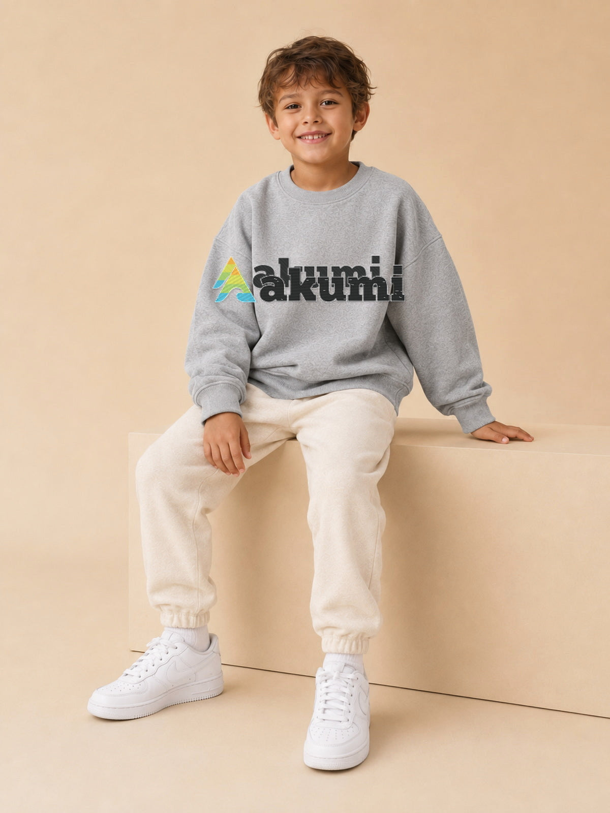 Akumi Little Varsitymark Crew Campus Grey seated studio view with realistic embroidered Akumi logo