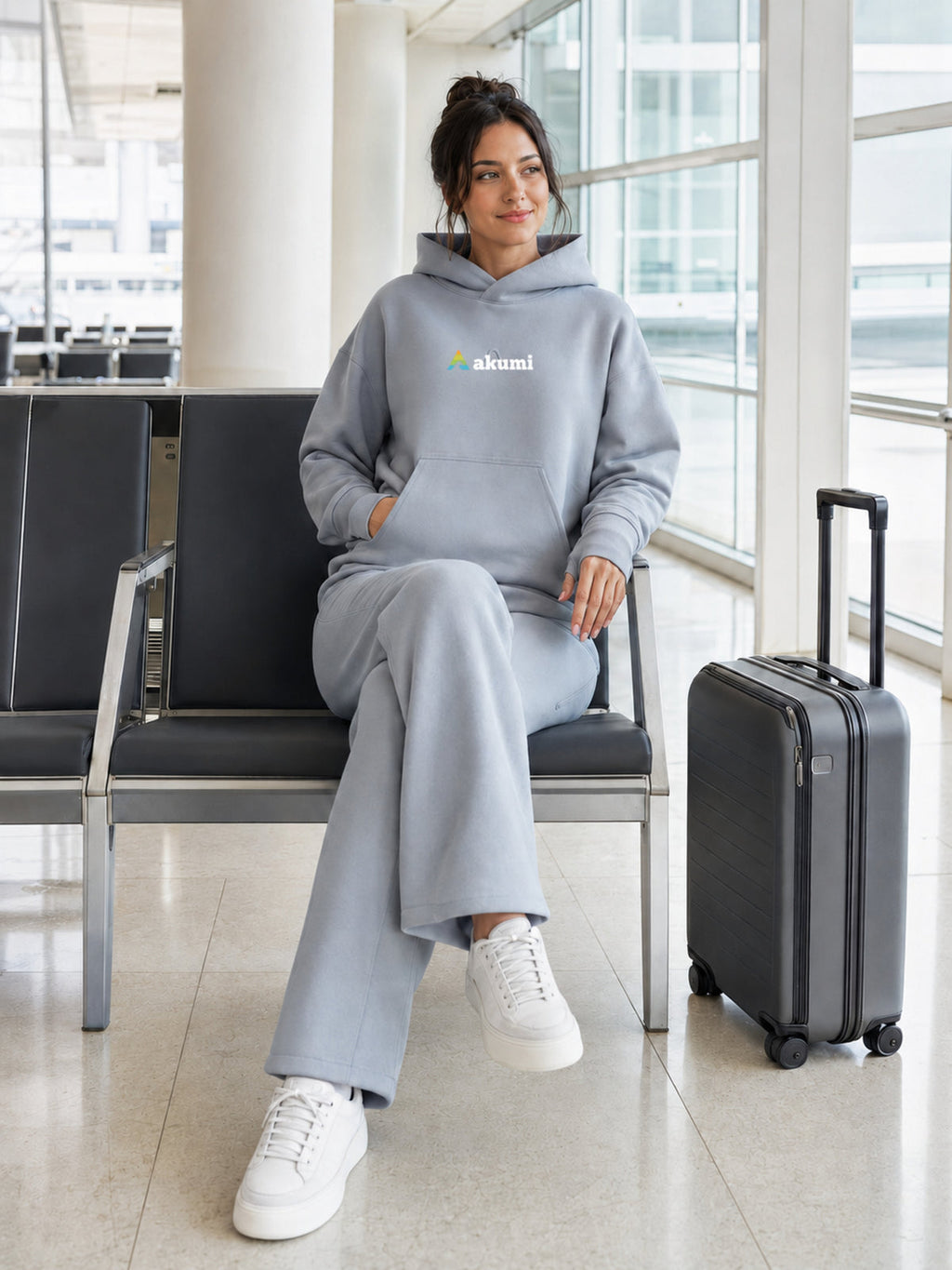 Akumi Quiet Transit Hoodie in Slate Mist, seated airport lifestyle