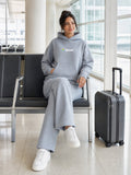Akumi Quiet Transit Hoodie in Slate Mist, seated airport lifestyle