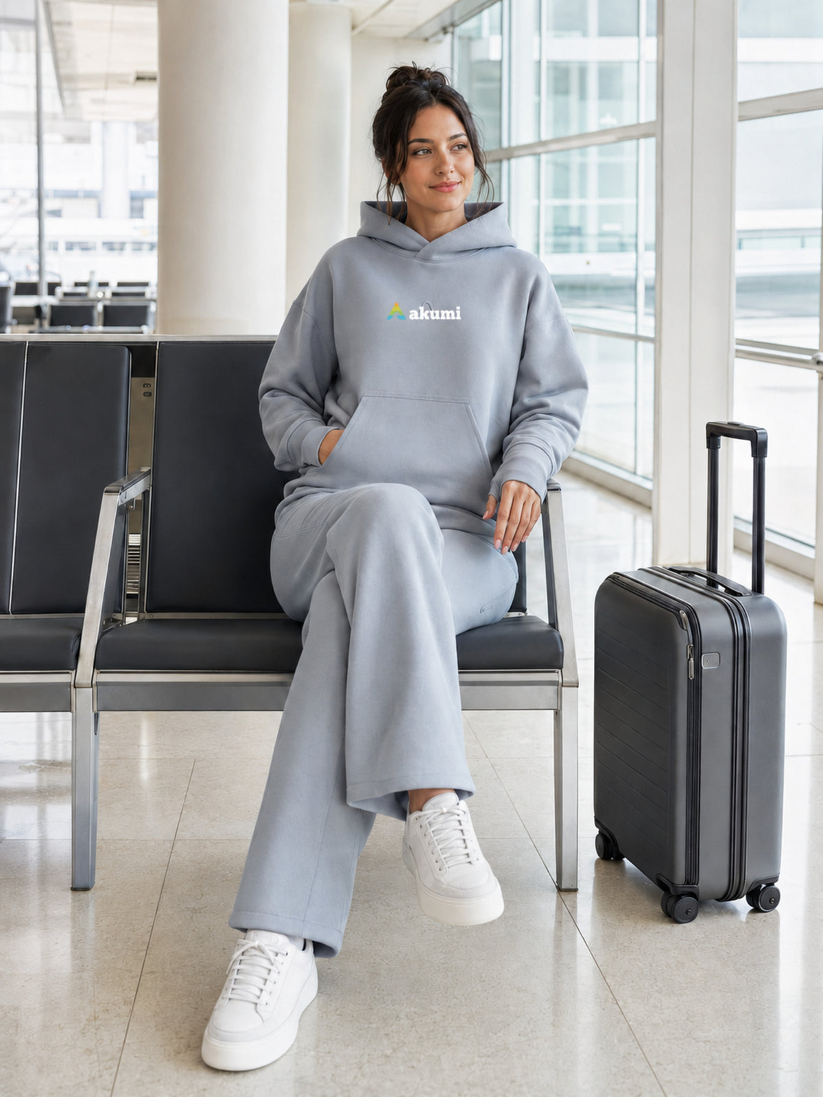 Akumi Quiet Transit Hoodie in Slate Mist, seated airport lifestyle
