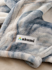 Close-up of Akumi Shoreline Blanket plush fabric and Akumi woven label