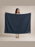 Akumi Still Blanket in Dusk Blue held open with consistent full-color Akumi woven label