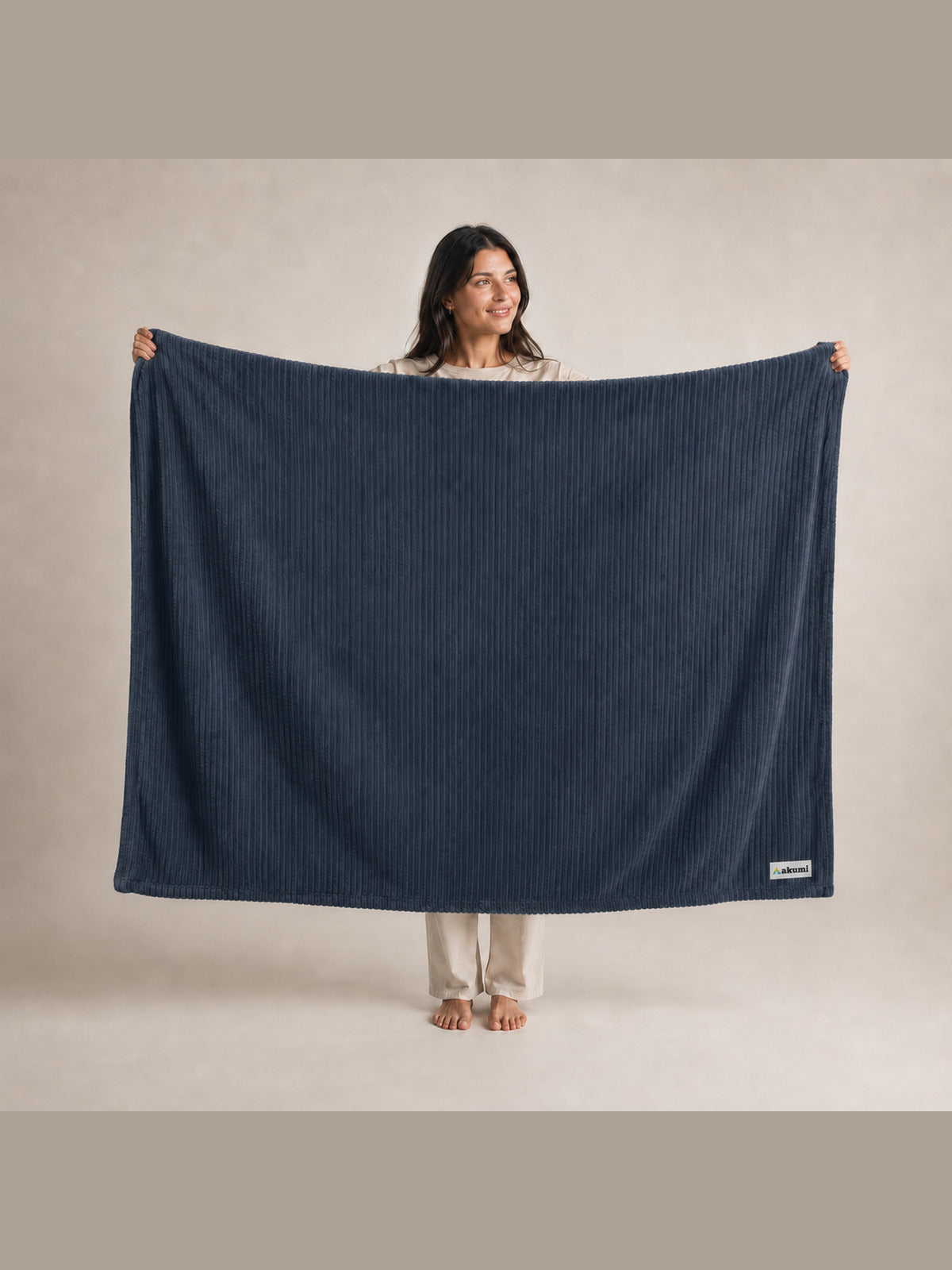 Akumi Still Blanket in Dusk Blue held open with consistent full-color Akumi woven label
