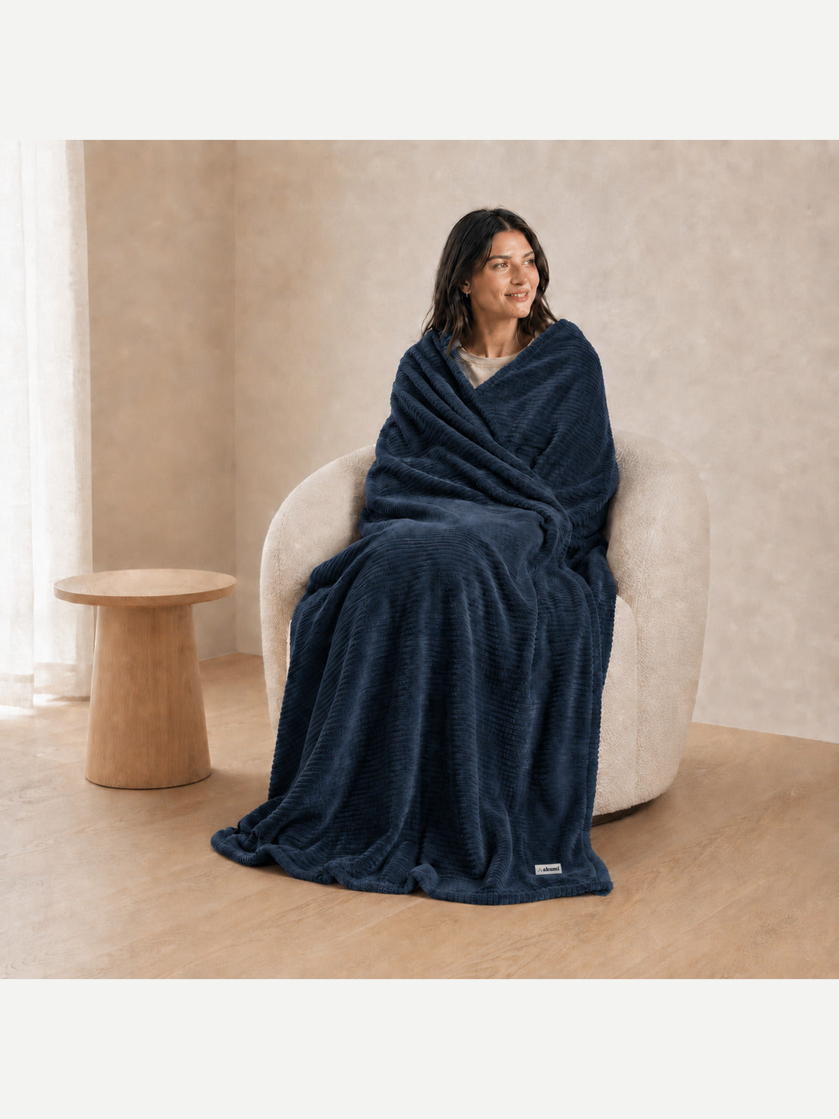 Woman wrapped in Akumi Still Blanket with consistent woven label scale