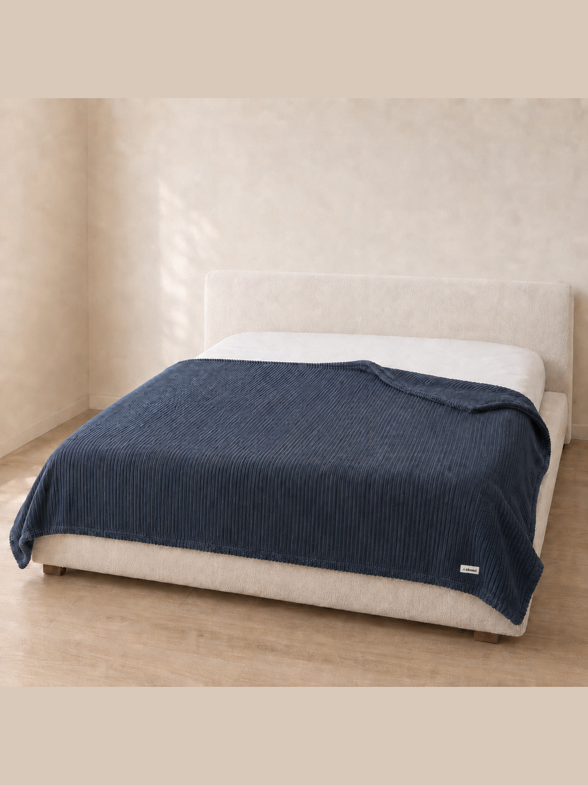 Akumi Still Blanket on bed with consistent woven label scale
