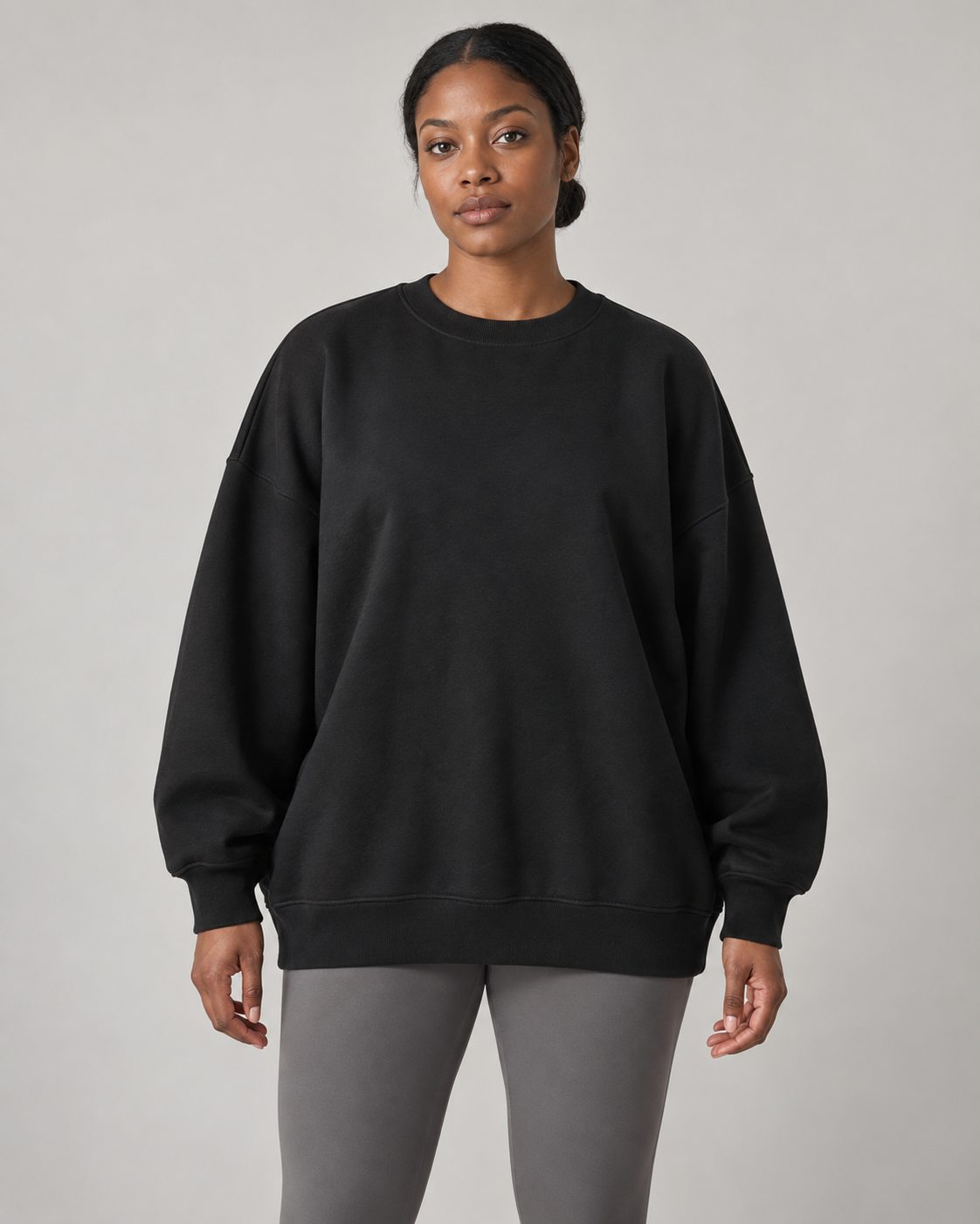 AI-generated design concept: woman wearing the proposed Stillform Oversized Crew in Onyx, front view.