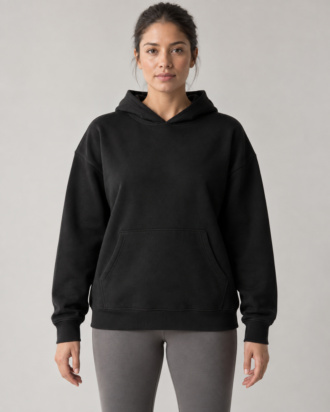 AI-generated design concept: woman wearing the proposed Stillform Relaxed Pullover Hoodie in Onyx, front view.