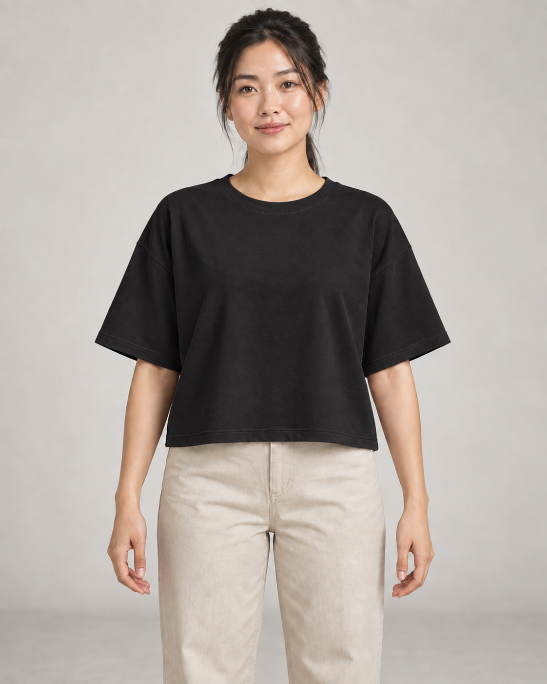 Generated concept mockup: Women's Still Box Tee in Black, front view on model.