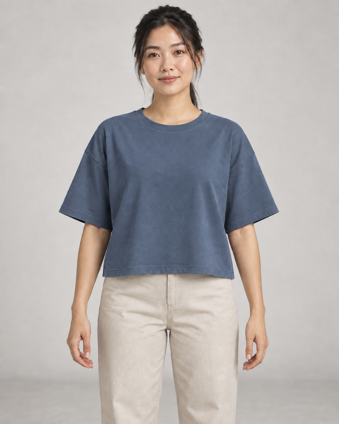 Generated concept mockup: Women's Still Box Tee in Slate, front view on model.