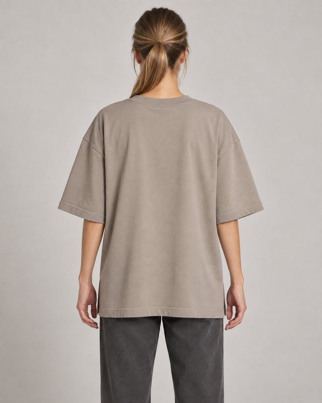 Generated concept mockup: women's Still Oversized Tee in Stone, back view on model.