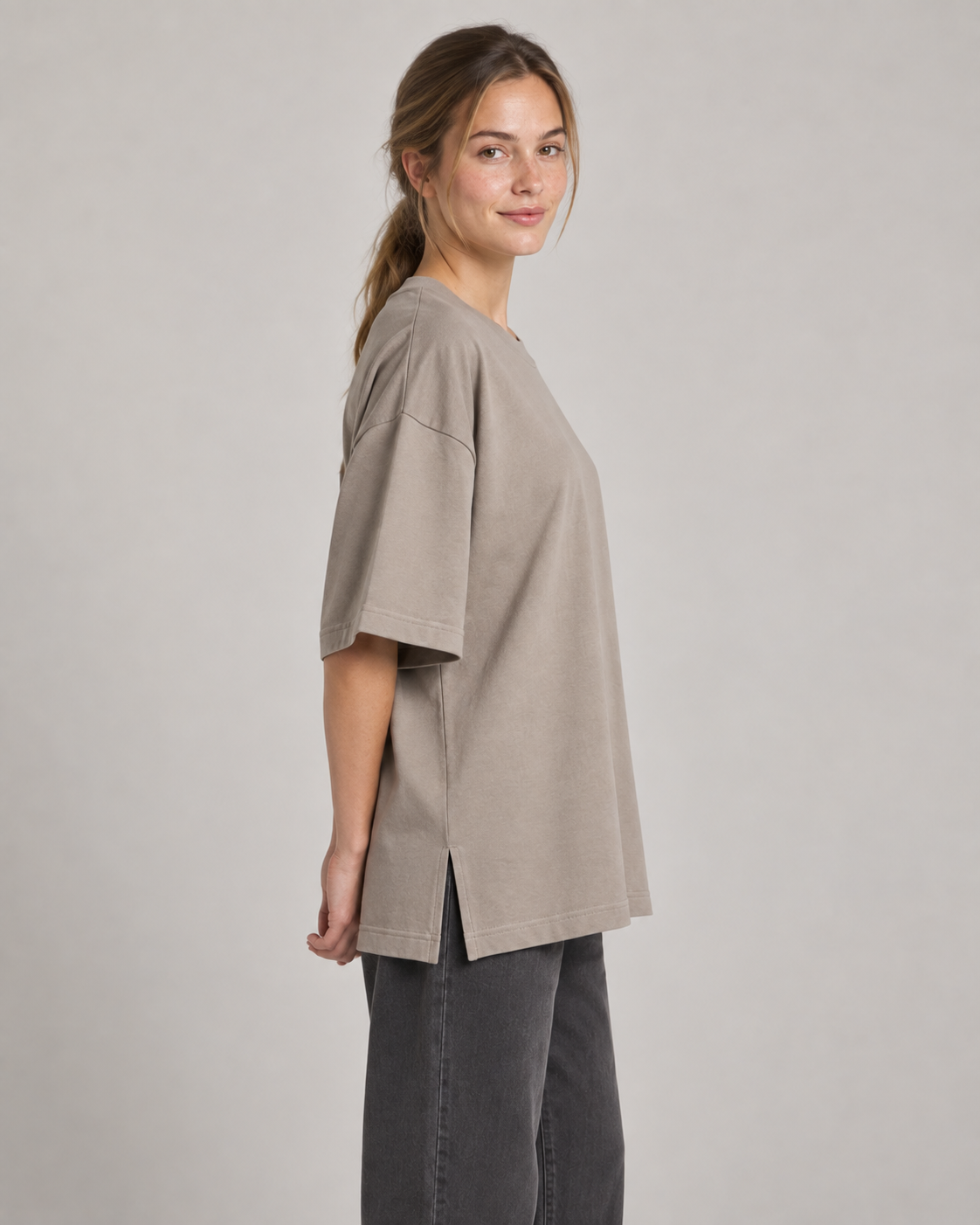 Generated concept mockup: women's Still Oversized Tee in Stone, side view on model.
