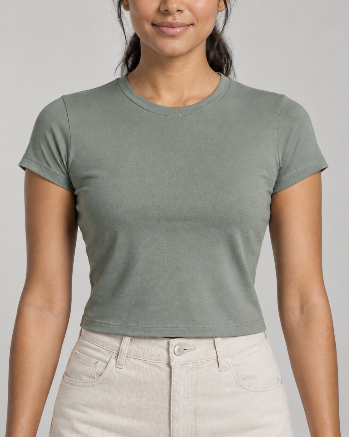 Generated concept mockup: Women's Balance Baby Tee in Eucalyptus, construction detail view highlighting crew neckline, close-fitting sleeve seam and cropped hem.
