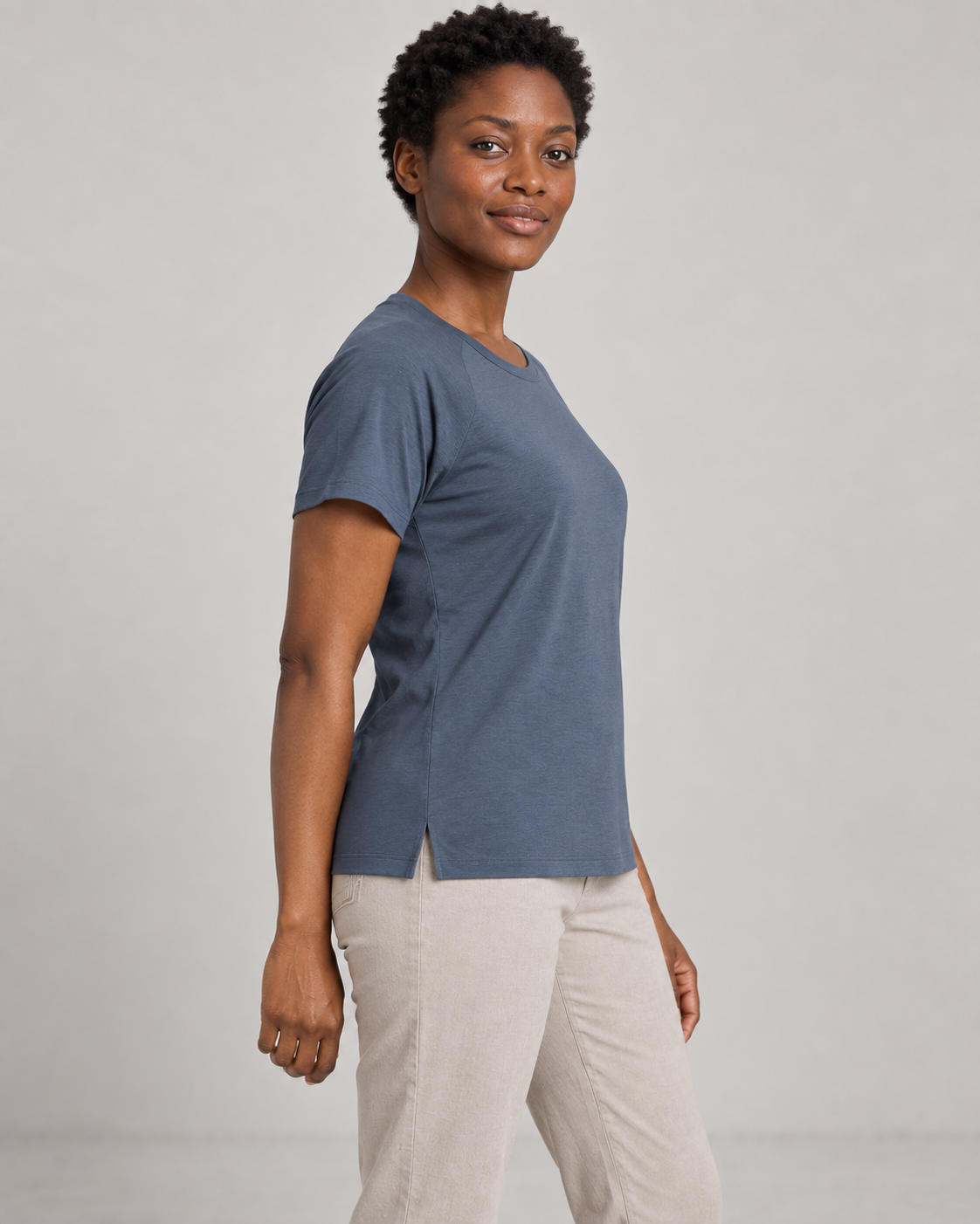 Generated concept mockup: women's Cadence Raglan Tee in Slate, side view on model.