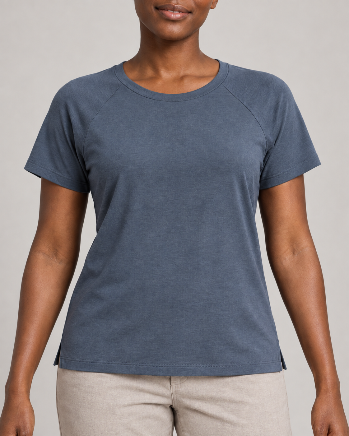 Generated concept mockup: Women's Cadence Raglan Tee in Slate, construction detail view highlighting raglan shoulder seams, crew neckline and small side openings.
